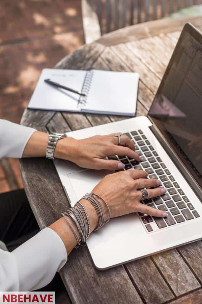 person typing on MacBook Pro on brown wooden table during daytime photo