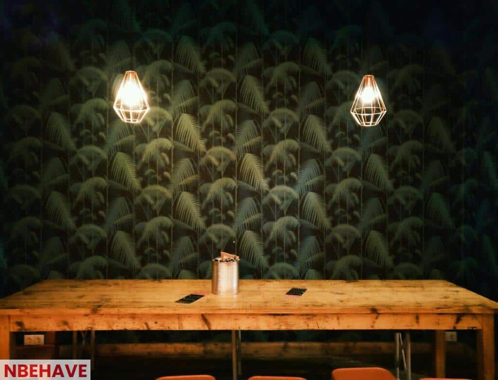 Cozy rustic interior featuring geometric pendant lamps and a large wooden table against a patterned wall.